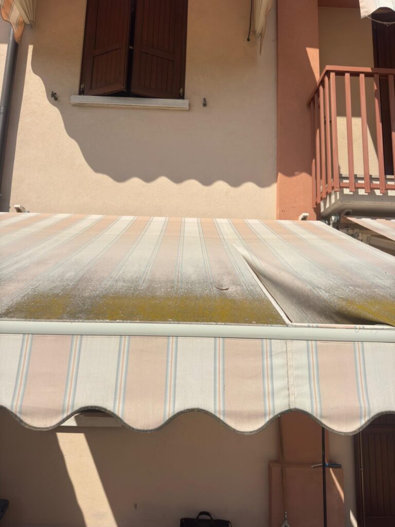 muffa e strappo sul telo di una tenda da sole non pulita prima dell'inverno
