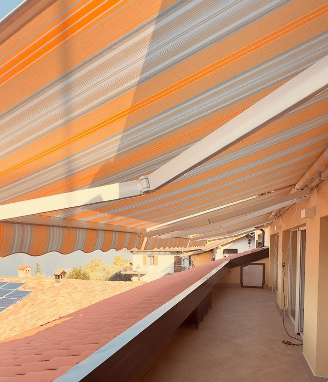 Tenda da sole a bracci con telo a righe su un terrazzo