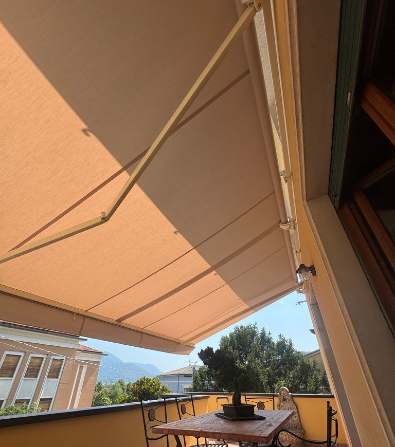 Tenda da sole motorizzata aperta su un balcone con sedie e tavolo